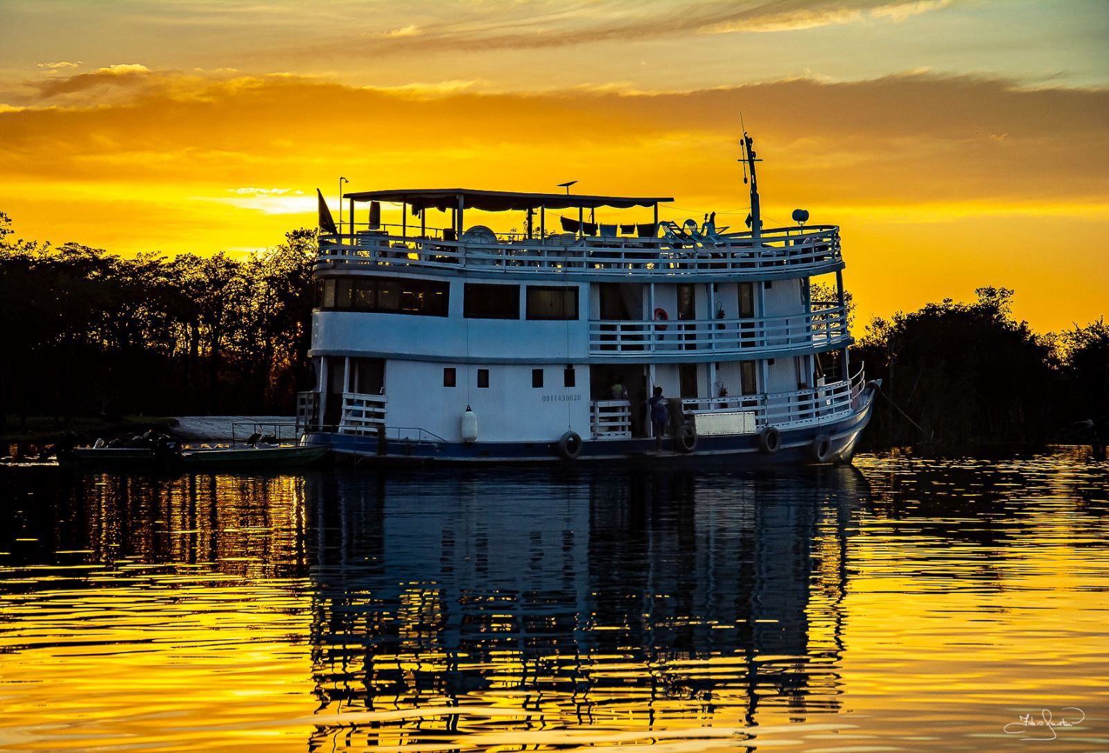 White Amazon river cruiser at golden-hour sunset on the Rio Negro — Manaus region, Brazil